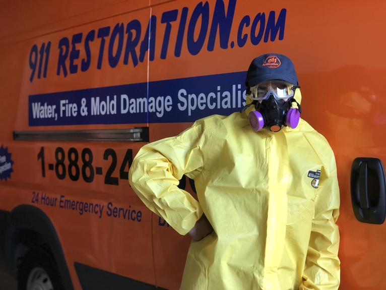 water damage restoration technician in front of 911 Restoration van