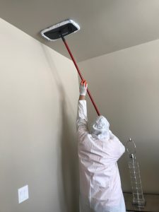 a fire damage restoration technician cleans a ceiling